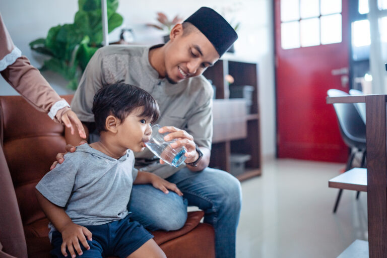 asian muslim father help his son drink water