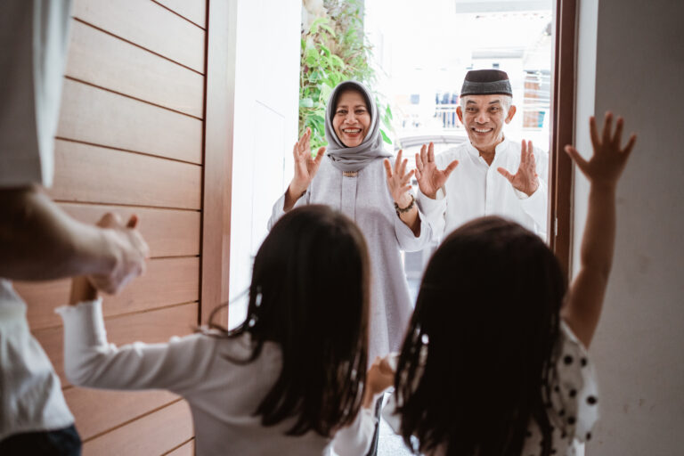 excited asian muslim grandparents visiting their grandchildren home