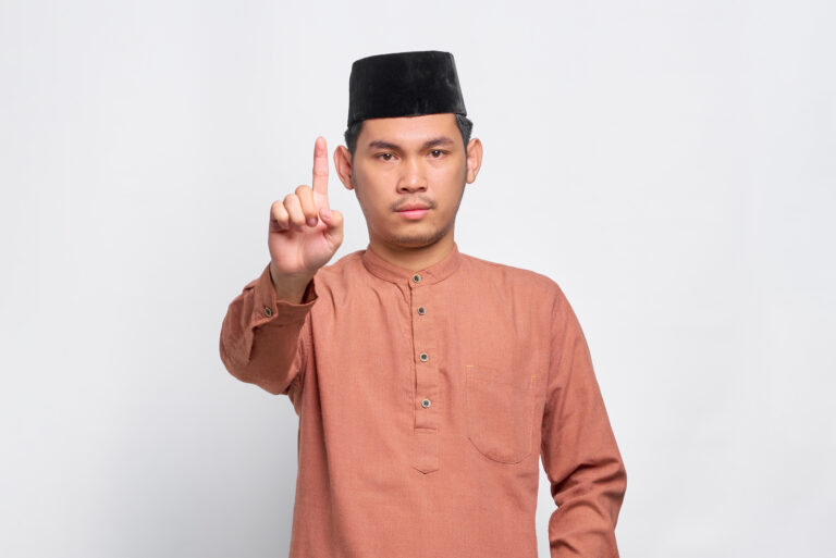 serious young asian muslim man showing stop gesture isolated white background